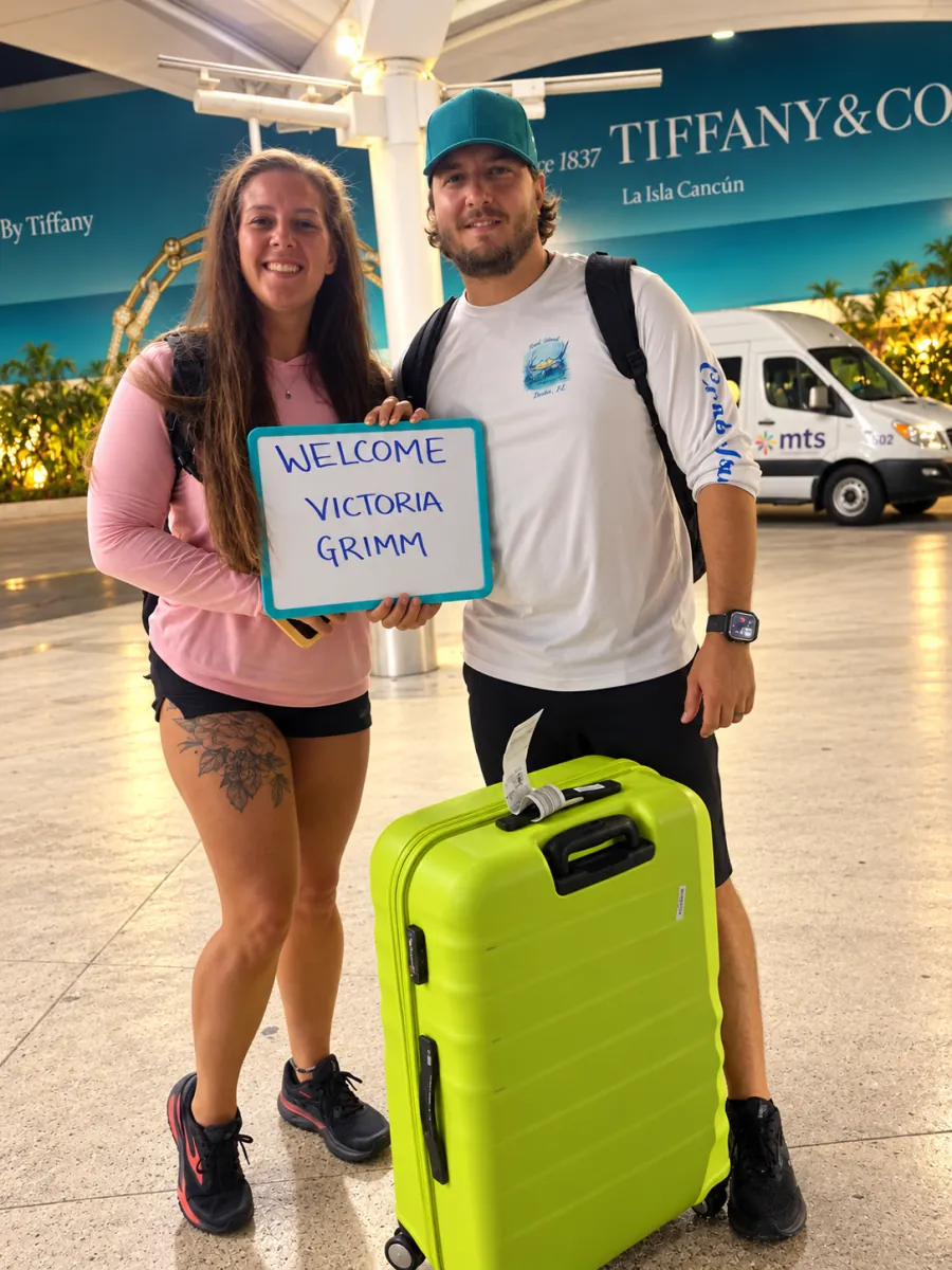Pareja con letrero de bienvenida en el aeropuerto